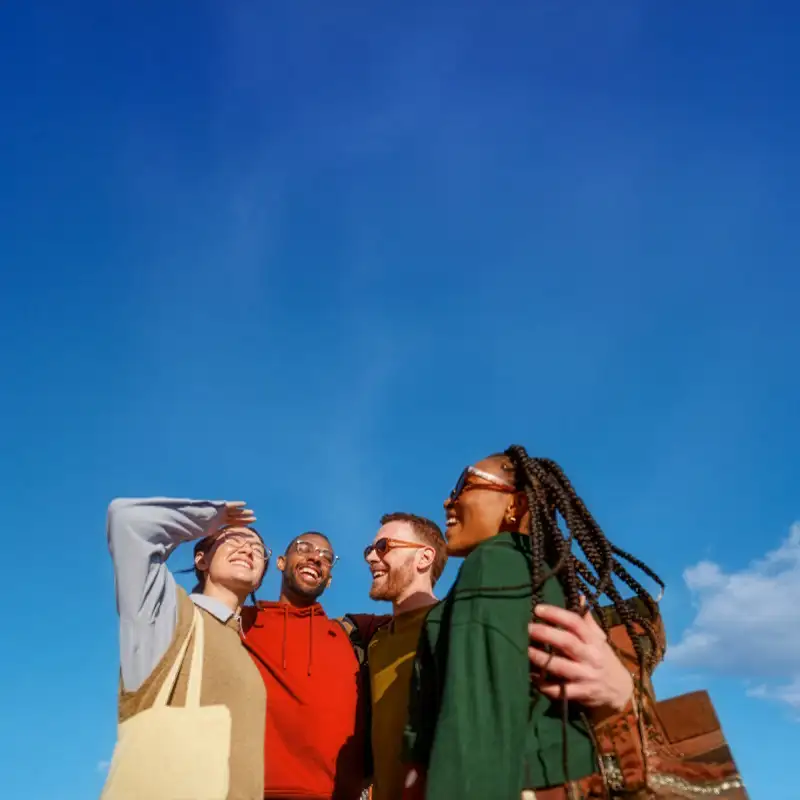 Un grupo de amigos sonriendo y mirando al cielo